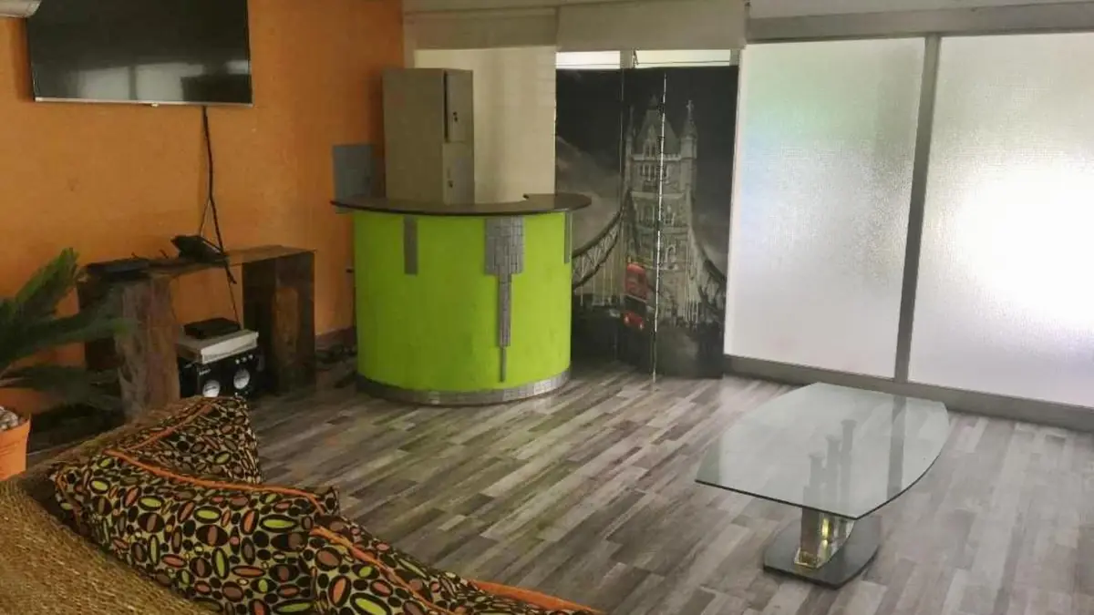 Salón de uso común de Serenade Lodging Rooms, con sofá de mimbre y TV